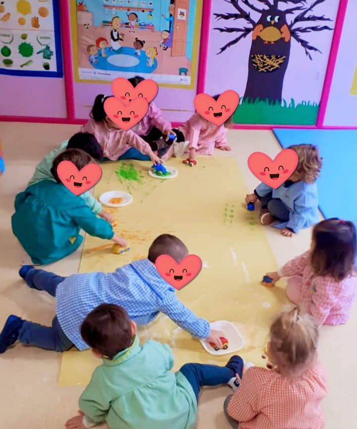 Un grupo de niños con corazones en sus caras están jugando en el suelo.