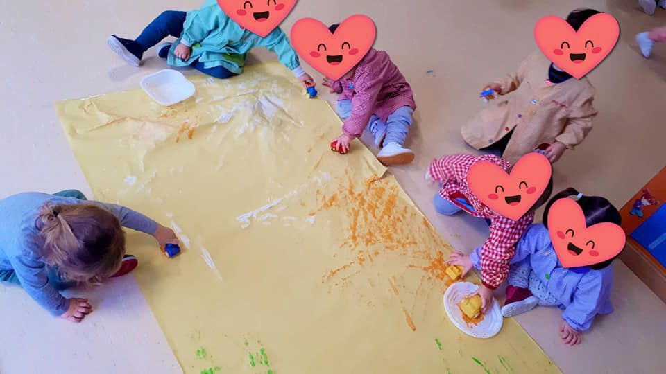 Un grupo de niños está sentado en el suelo jugando con una hoja de papel amarilla.