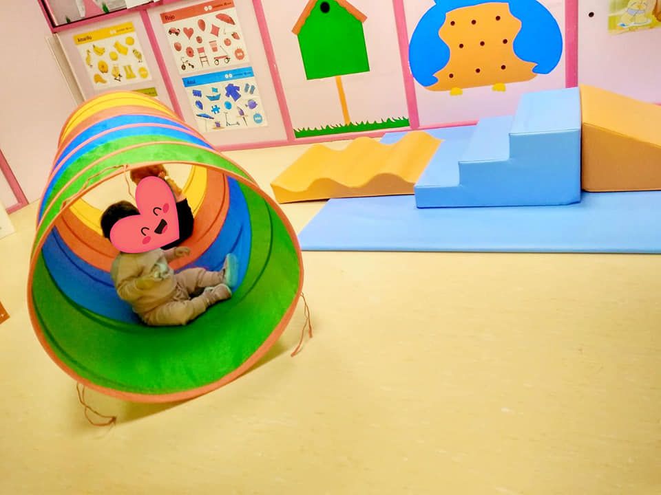 Un bebé está jugando en un túnel colorido en una sala de juegos.