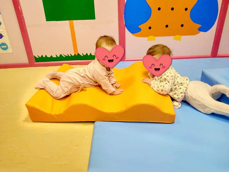 Dos bebés gatean sobre una alfombra amarilla con corazones en sus caras.