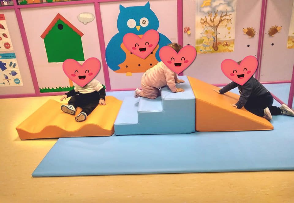 Tres bebés con corazones en sus caras están jugando en una sala de juegos.