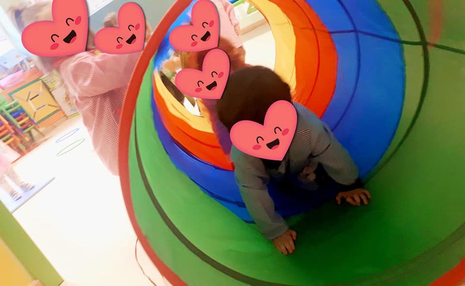 Un niño se arrastra a través de un túnel colorido con corazones en él.