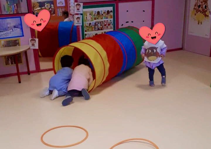 Un grupo de niños está jugando en una habitación con un túnel colorido.