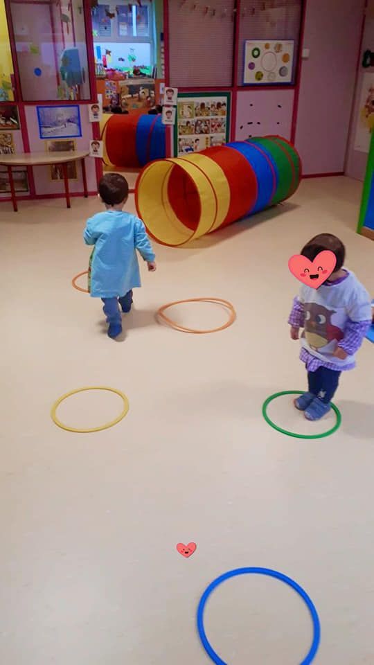 Dos niños están jugando en una habitación con círculos y un túnel.