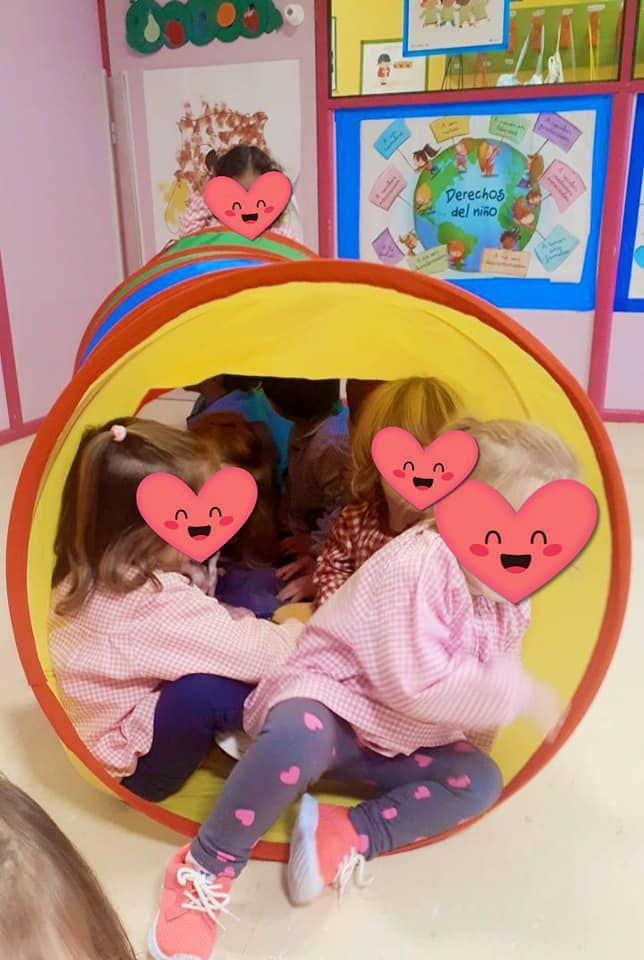 Un grupo de niños juega en un túnel con corazones en sus caras.