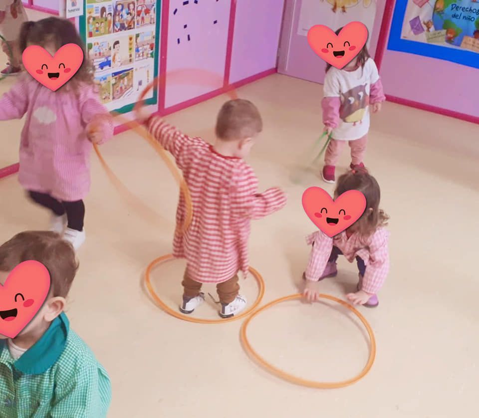 Un grupo de niños con corazones en sus caras están jugando con aros de hula hula
