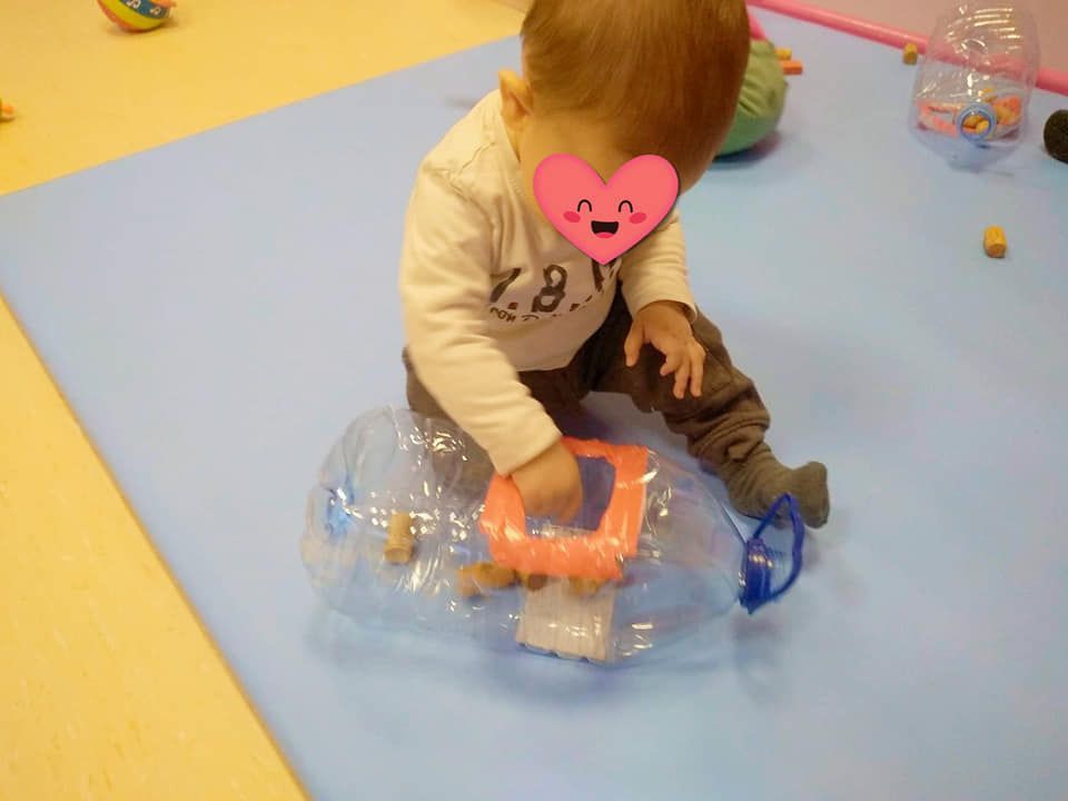 Un bebé está sentado sobre una alfombra azul jugando con un juguete.