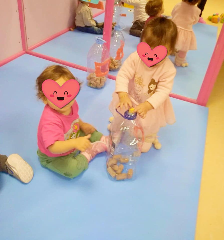 Dos niñas que llevan máscaras de corazón juegan con una botella de agua.