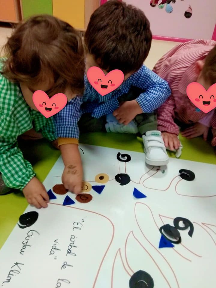 Tres niños con corazones en sus caras están jugando con un trozo de papel.