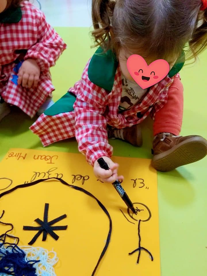 Una niña con un corazón en la cara está dibujando en un trozo de papel.