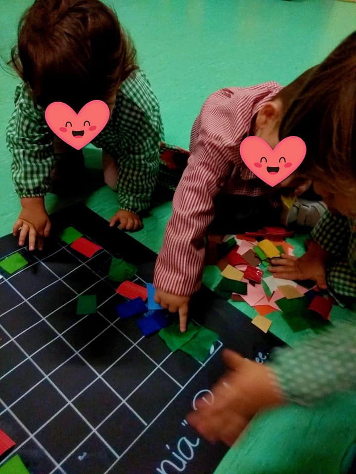 Dos niños con corazones rosas en sus caras están jugando en una alfombra que dice nia