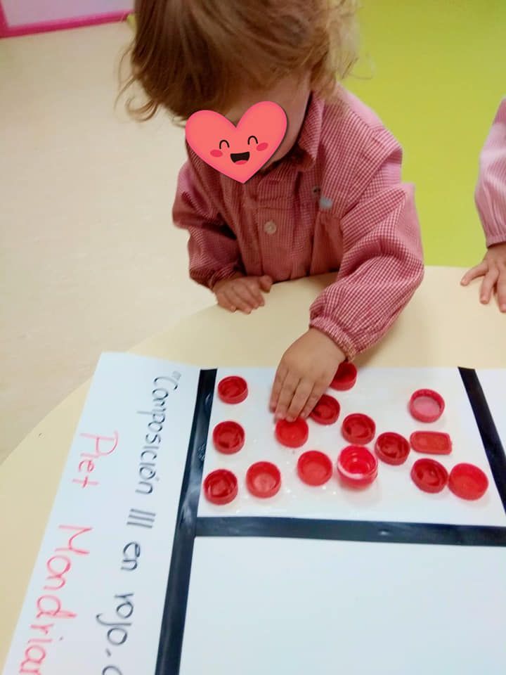 Una niña con un corazón en la cara está jugando con gorras rojas.