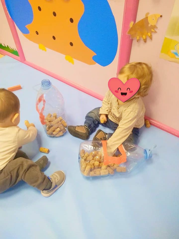Dos bebés están sentados en el suelo con una bolsa de corchos.