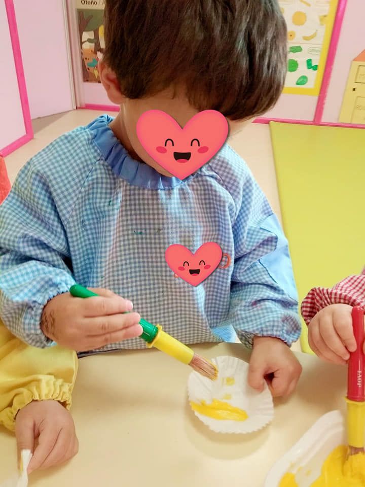 Un niño pequeño está sentado en una mesa con un corazón en su camisa.