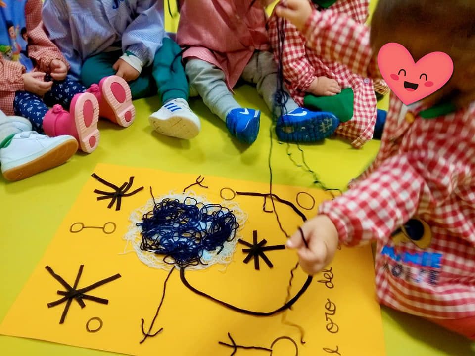 Un grupo de niños está sentado en el suelo jugando con hilo.