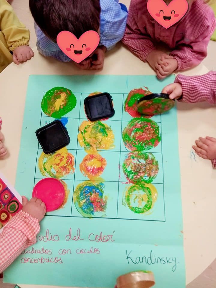 Un grupo de niños están sentados alrededor de una mesa con un cartel que dice Kandinsky.