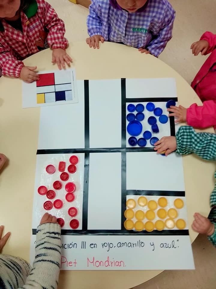 Un grupo de niños están sentados alrededor de una mesa con un trozo de papel que dice Pie Mondrian.
