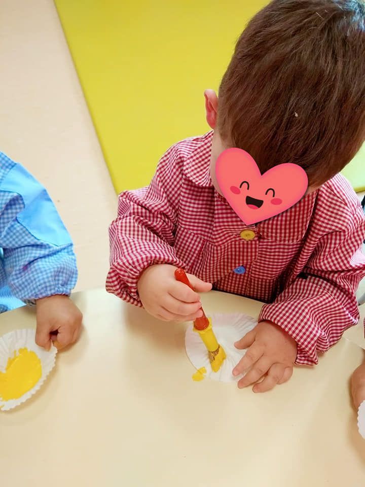 Un niño pequeño con un corazón en su cara está pintando en un plato de papel.
