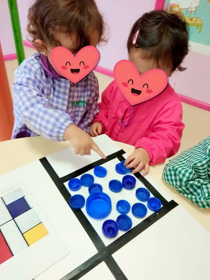 Dos niñas con corazones en sus caras están jugando con tapas de botellas azules
