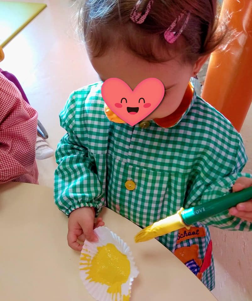 Una niña con un corazón en la cara pinta un cupcake