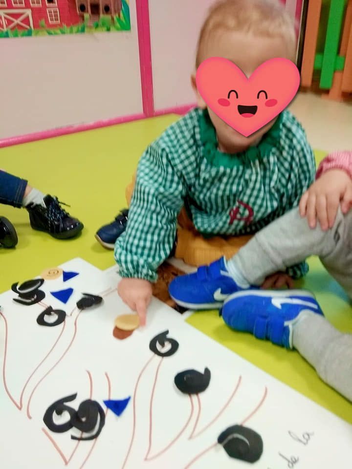 Un bebé con un corazón en la cara está jugando con números.