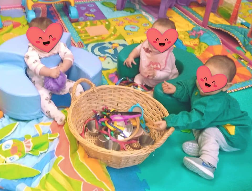 Un grupo de bebés está jugando con una canasta de juguetes.