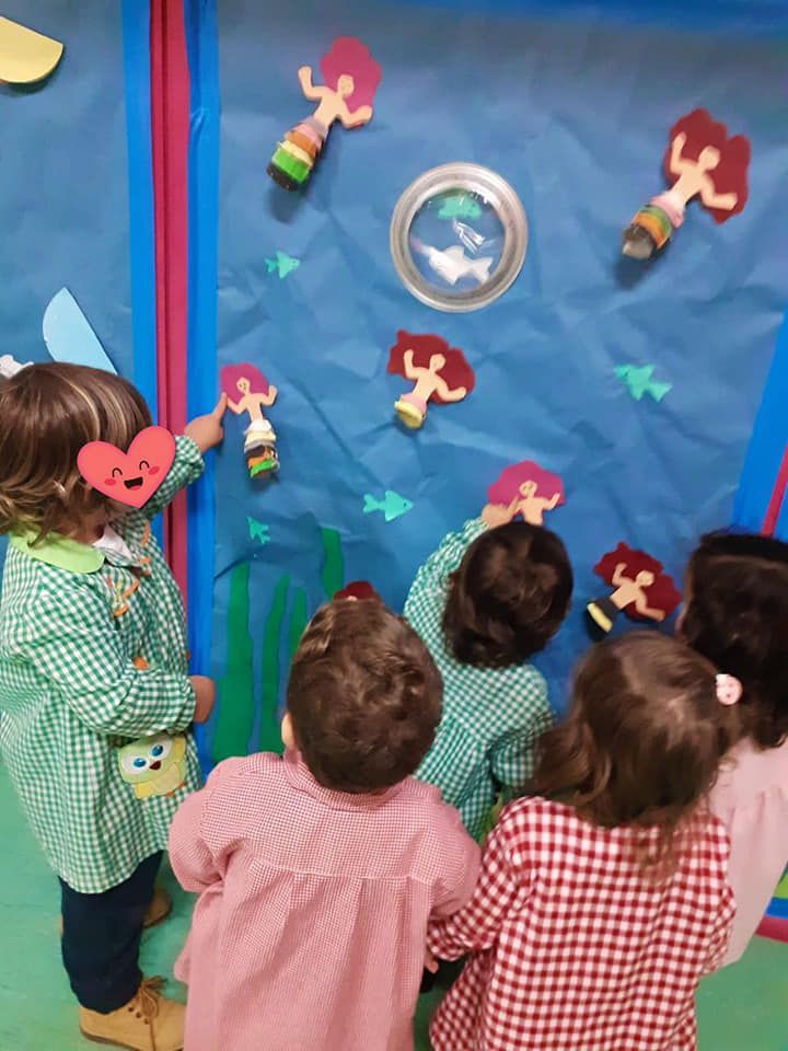 Un grupo de niños mira una pared con personas de papel.