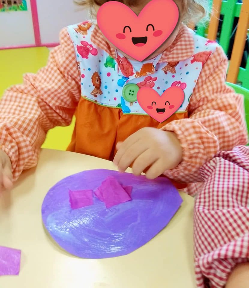 Una niña con un corazón en la cara está sentada en una mesa.