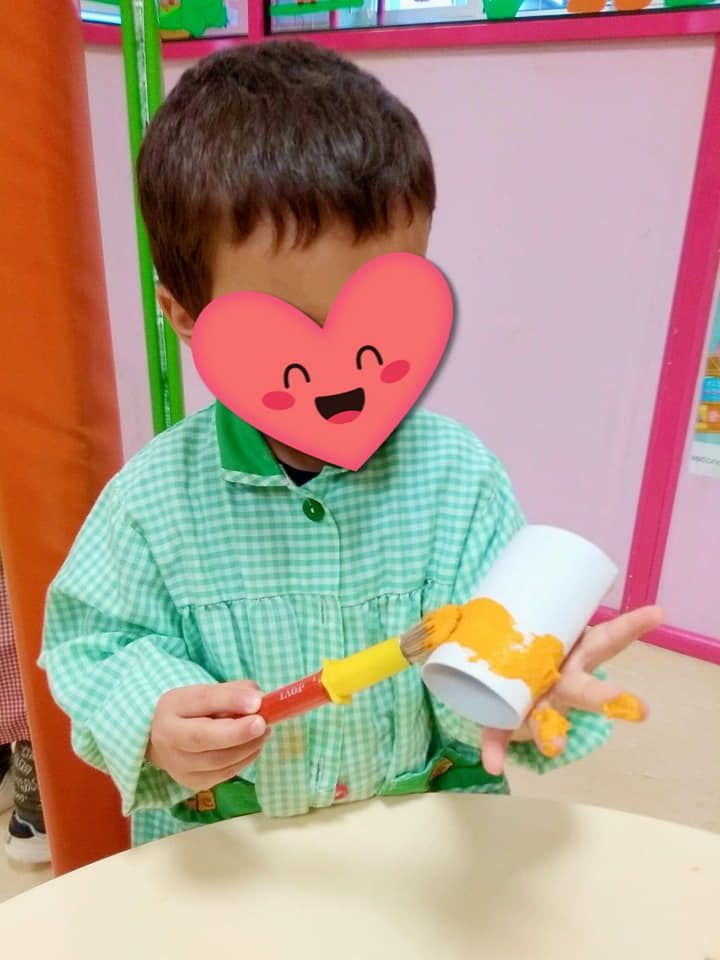 Un niño pequeño con un corazón en la cara sostiene un pincel.