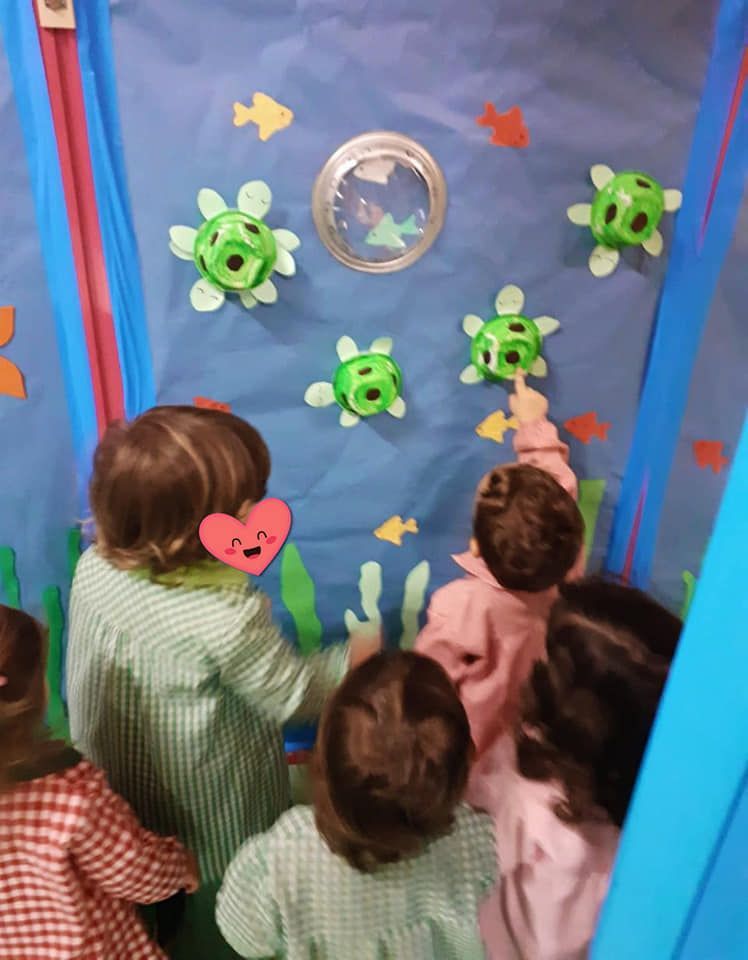 Un grupo de niños mira tortugas marinas en una pared.