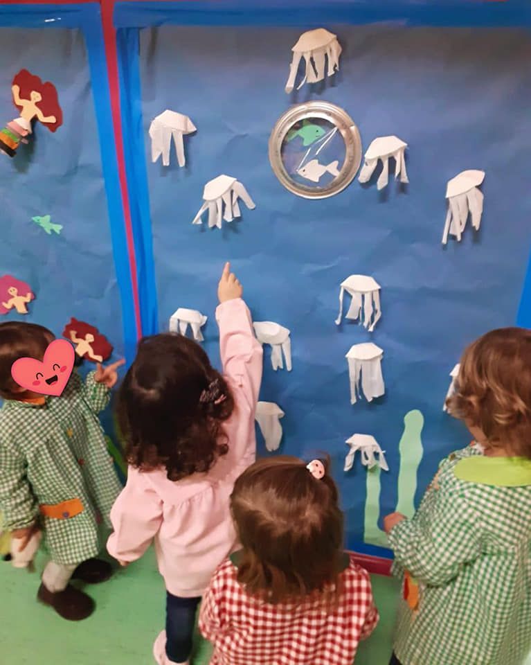 Un grupo de niños mira una pared con medusas.