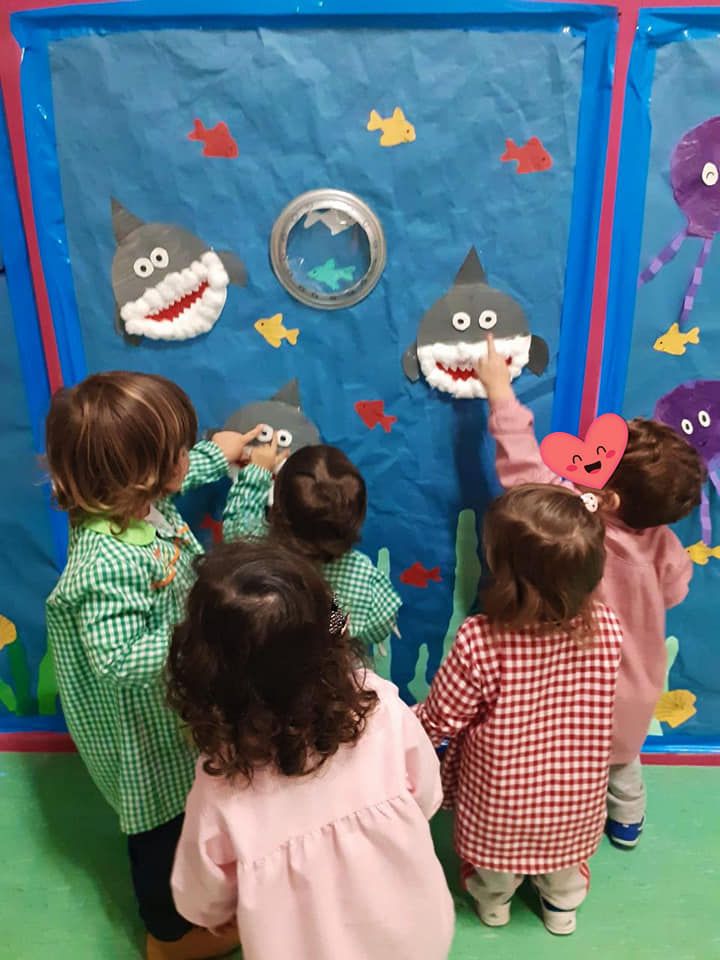 Un grupo de niños está parado alrededor de una pared con tiburones.