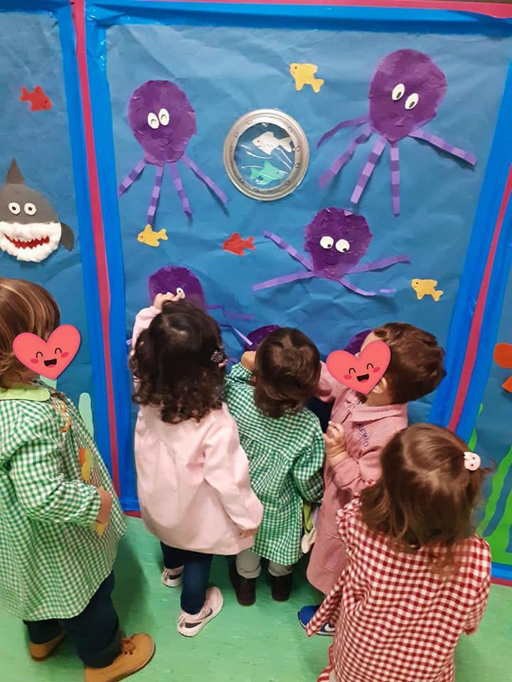 Un grupo de niños mira una pared con pulpos y peces.
