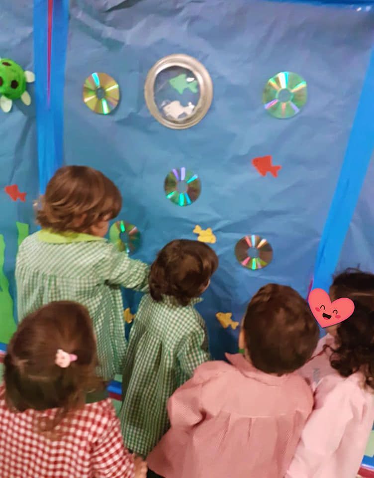 Un grupo de niños mira una pecera hecha con CD.