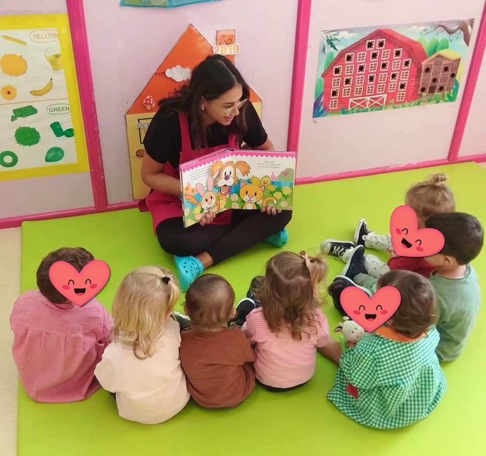 Una mujer está leyendo un libro a un grupo de niños.