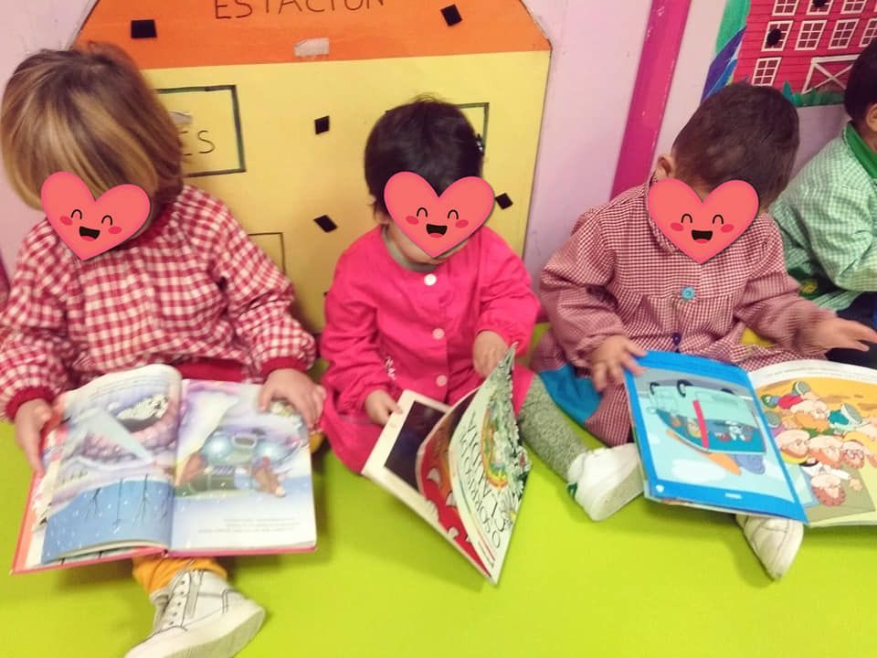 Un grupo de niños están sentados en el suelo leyendo libros.