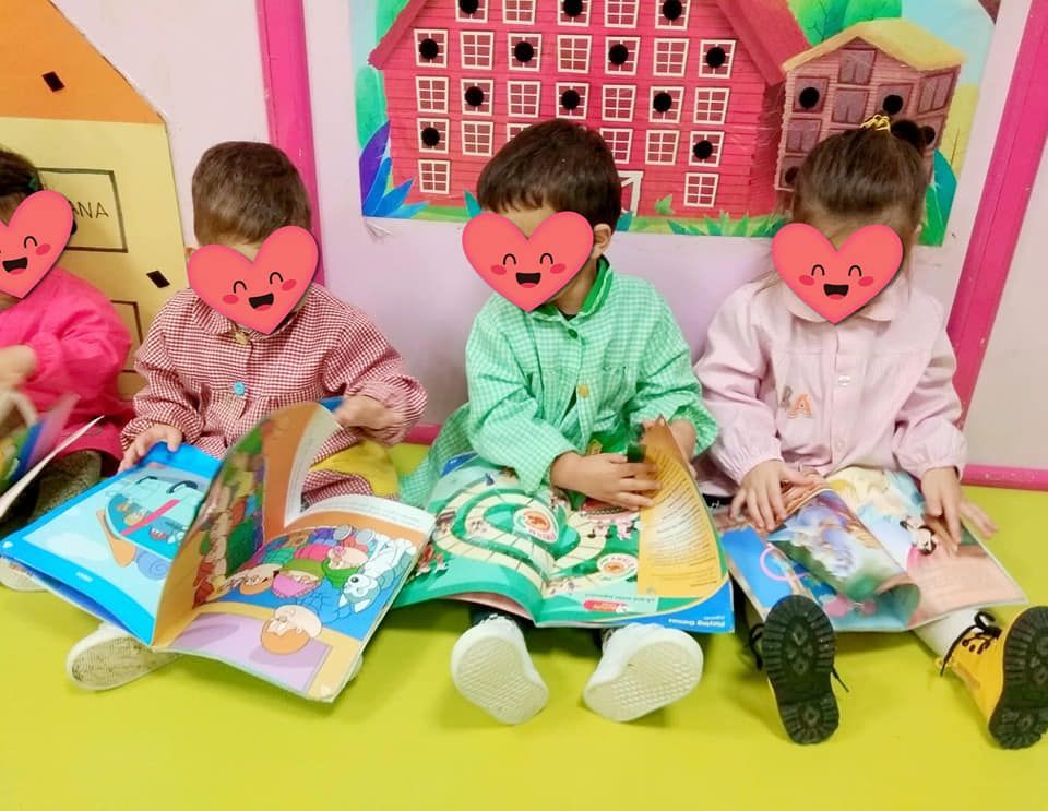 Un grupo de niños están sentados en el suelo leyendo libros.