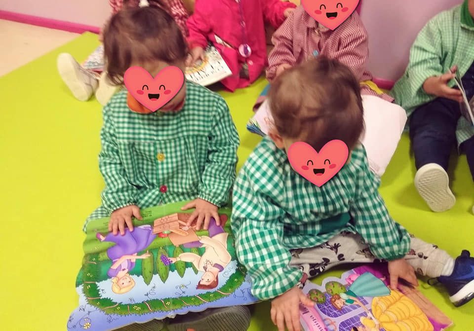 Un grupo de niños están sentados en el suelo leyendo libros.