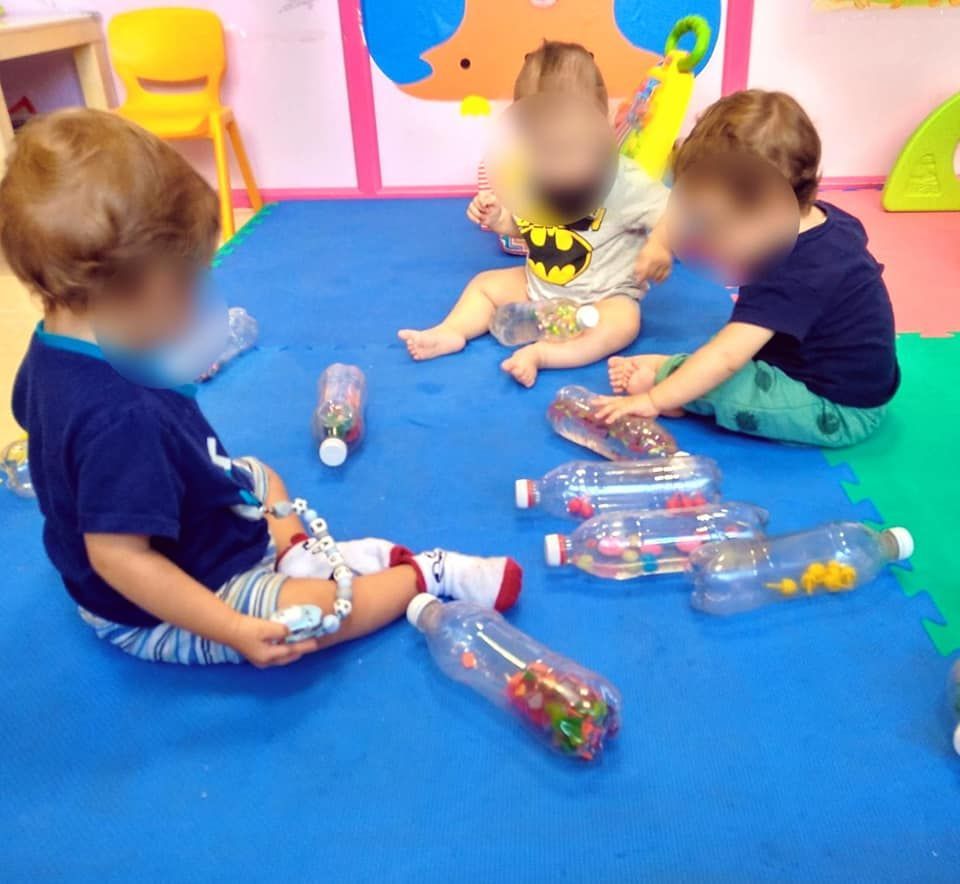 Un bebé que lleva una camiseta de Batman se sienta en una alfombra azul.