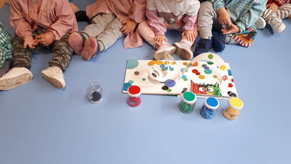 Un grupo de niños está sentado en el suelo jugando con pintura.