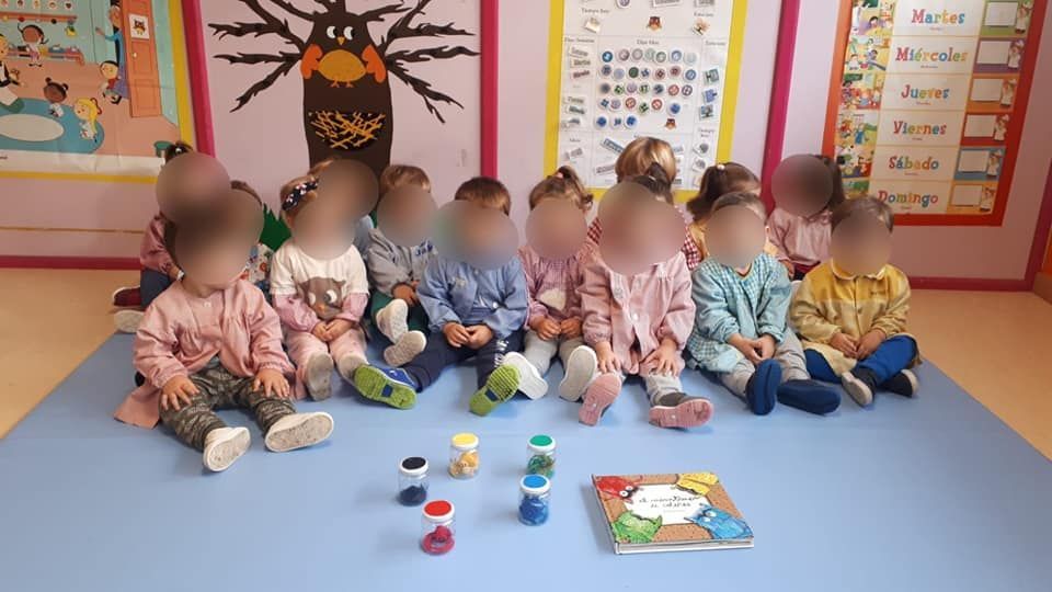 Un grupo de niños está sentado en el suelo en un aula.