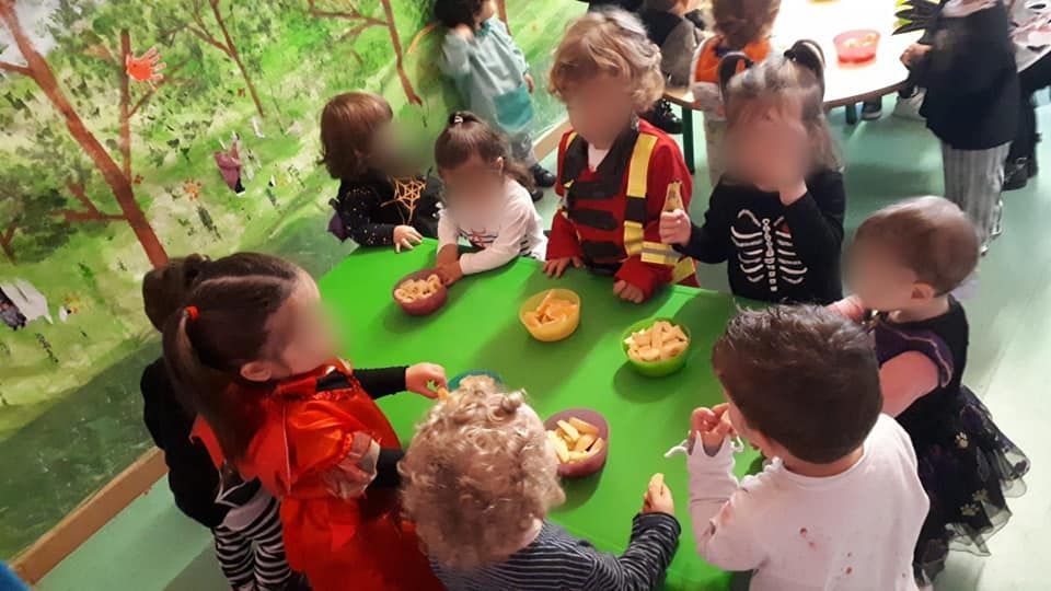 Un grupo de niños están sentados alrededor de una mesa comiendo comida.