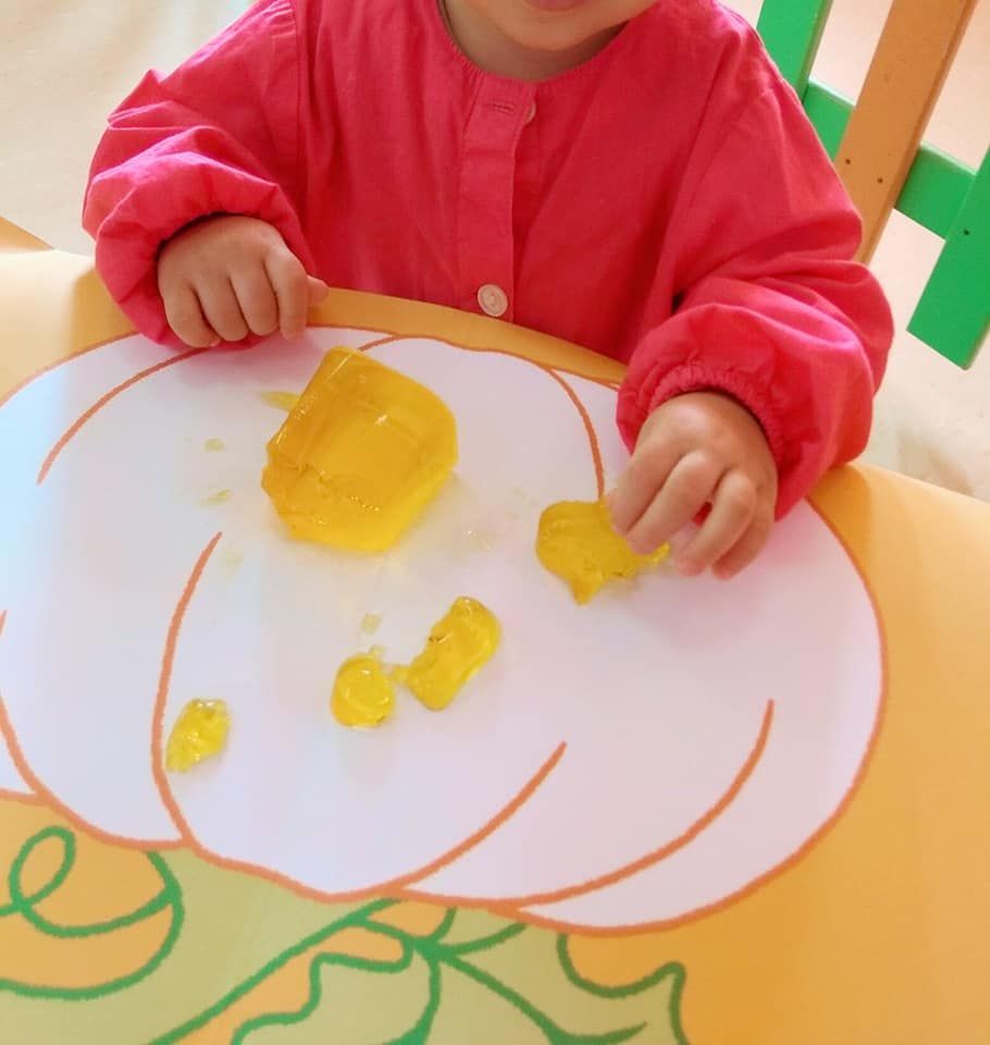 Una niña con una camisa rosa está jugando con ositos de goma amarillos.