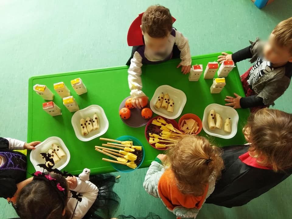 Un grupo de niños están sentados alrededor de una mesa con platos de comida.