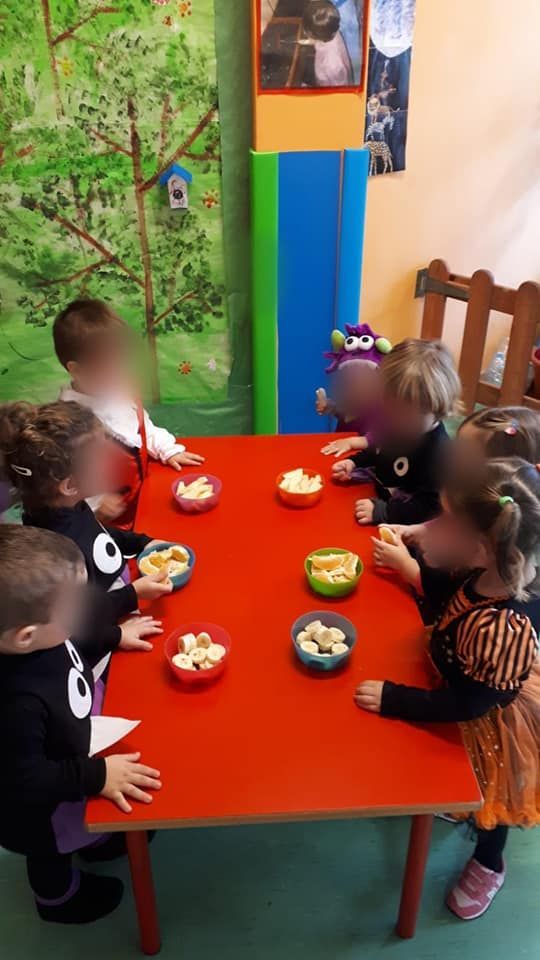 Un grupo de niños está sentado en una mesa roja comiendo comida.
