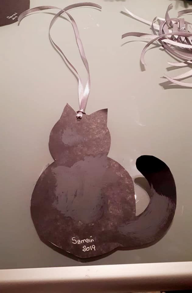 Un adorno con forma de gato negro está sentado sobre una mesa.