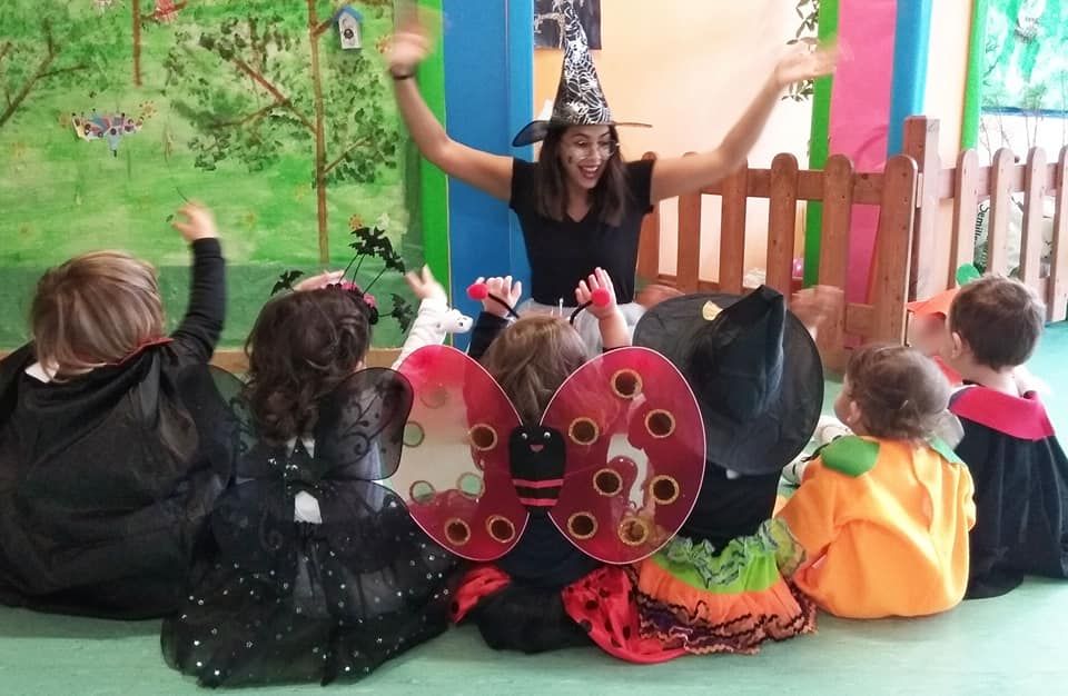 Una mujer con un sombrero de bruja está rodeada de niños vestidos con disfraces de Halloween.