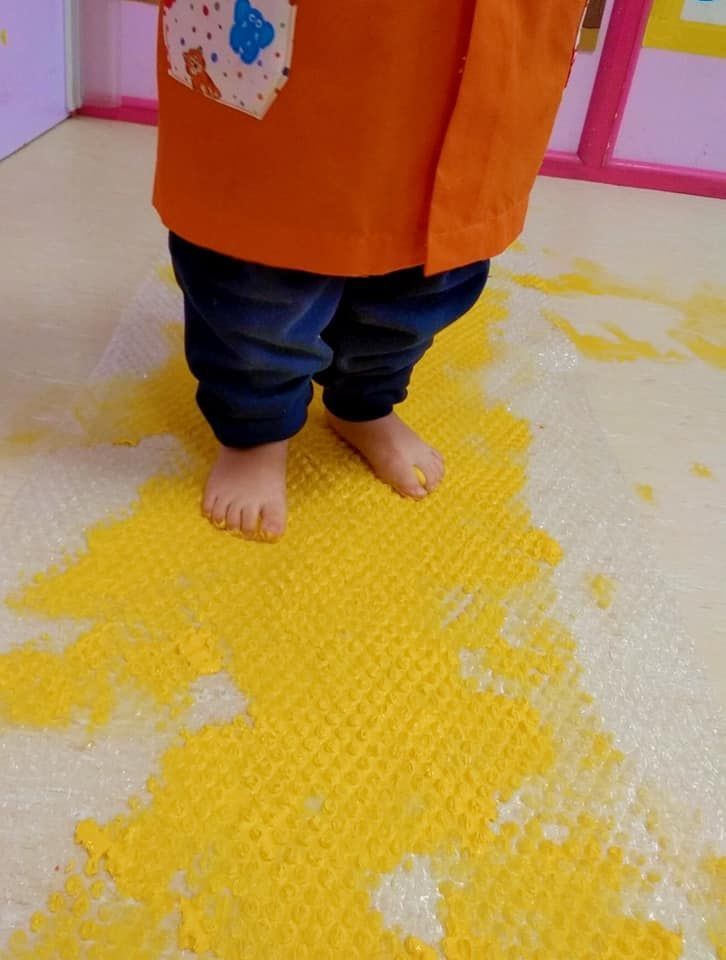 Un niño está parado sobre una alfombra amarilla en el suelo.