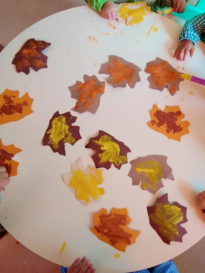 Los niños están sentados en una mesa con hojas pintadas en ella.
