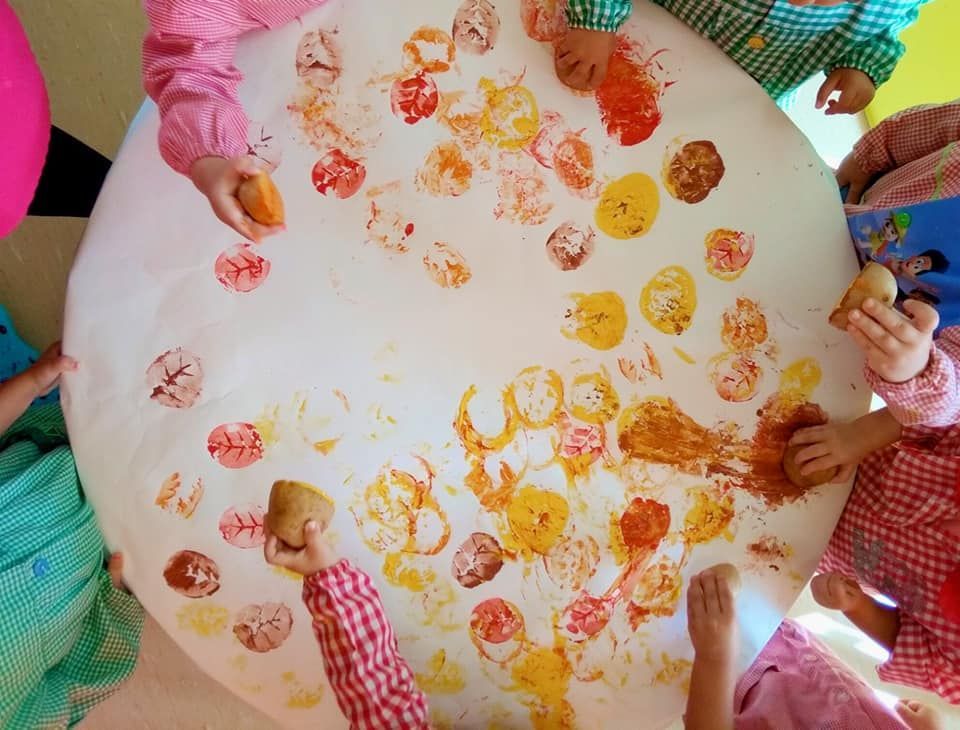 Un grupo de niños está jugando con pintura en una mesa.